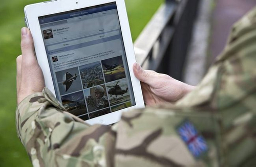 A serviceman accesses social media channels using an iPad, outside MOD Main Building in London